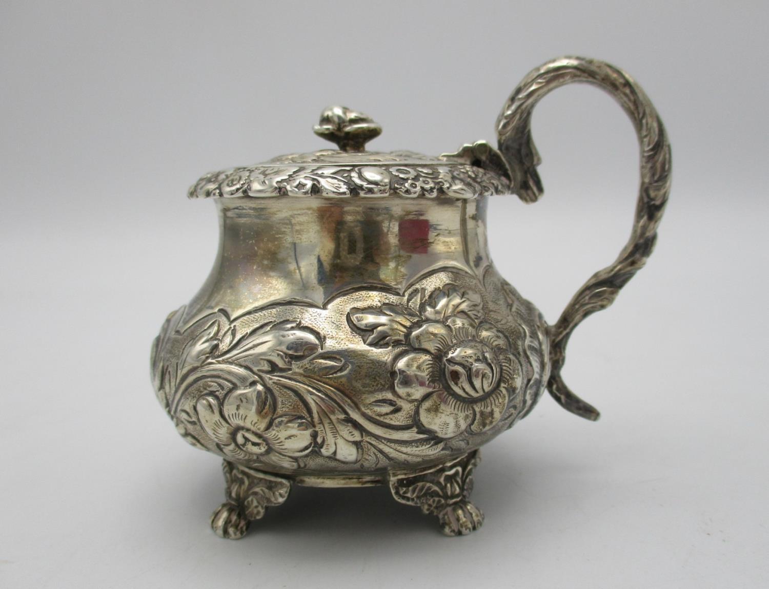 A George IV silver mustard pot by Joseph Biggs, London 1825, of bulbous form with embossed foliage