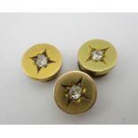 Three gold coloured metal dress studs, each set with a diamond