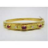 An 18ct gold bangle by Garrard, with hammered effect set with cabochon rubies and round cut