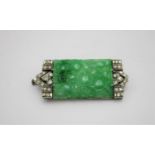 An early 20th century white coloured metal brooch the green jade coloured panel carved with fruiting