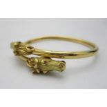 A Cartier style French gold double equestrian bangle, modelled with two horse heads inset with