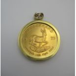 A gold Kruggerand, 1 oz, 1975, within a gold metal mount, total weight 43.6 grams