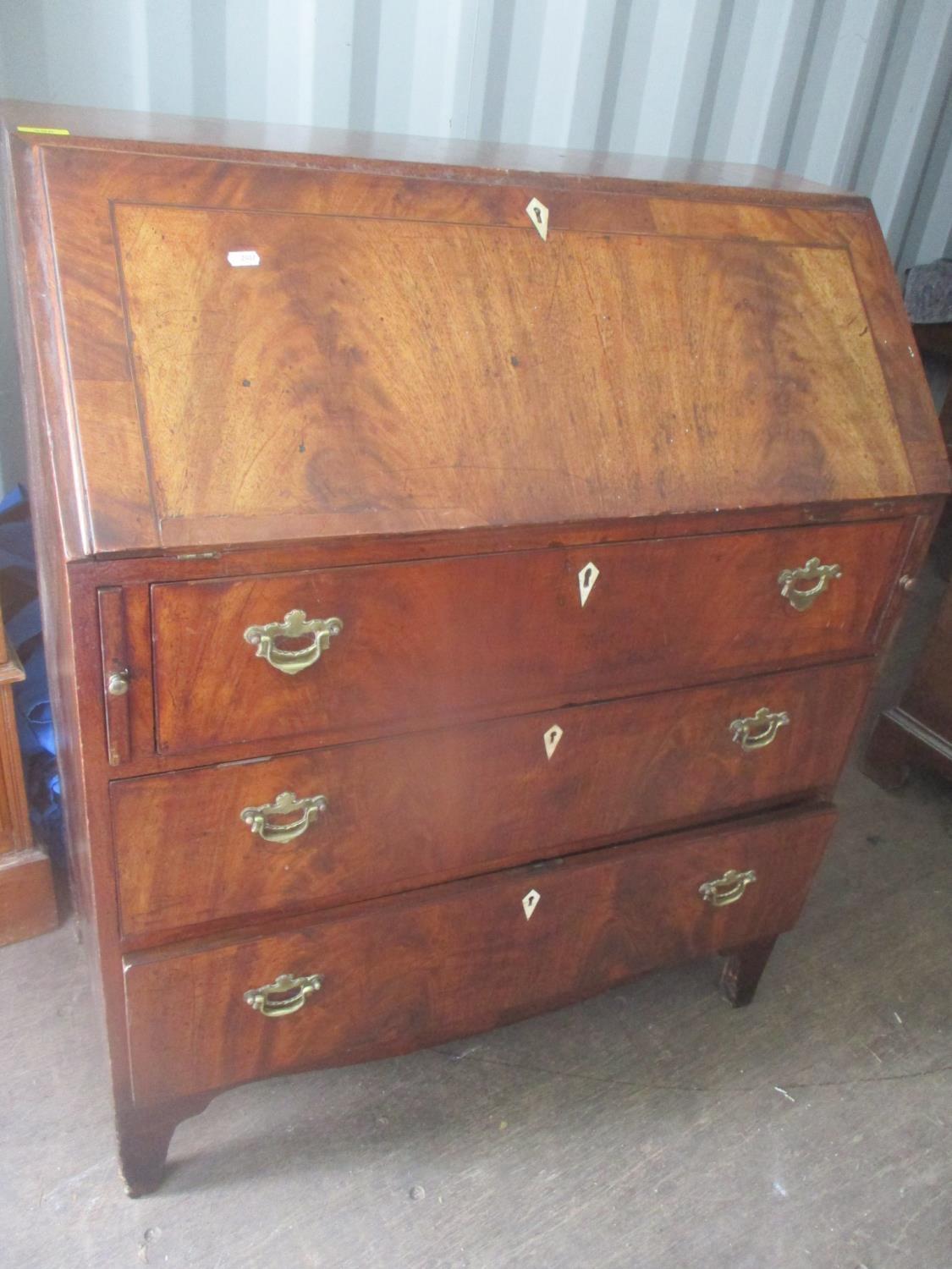 A Georgian mahogany bureau having a fall flap revealing fitted drawers and pigeonholes above three