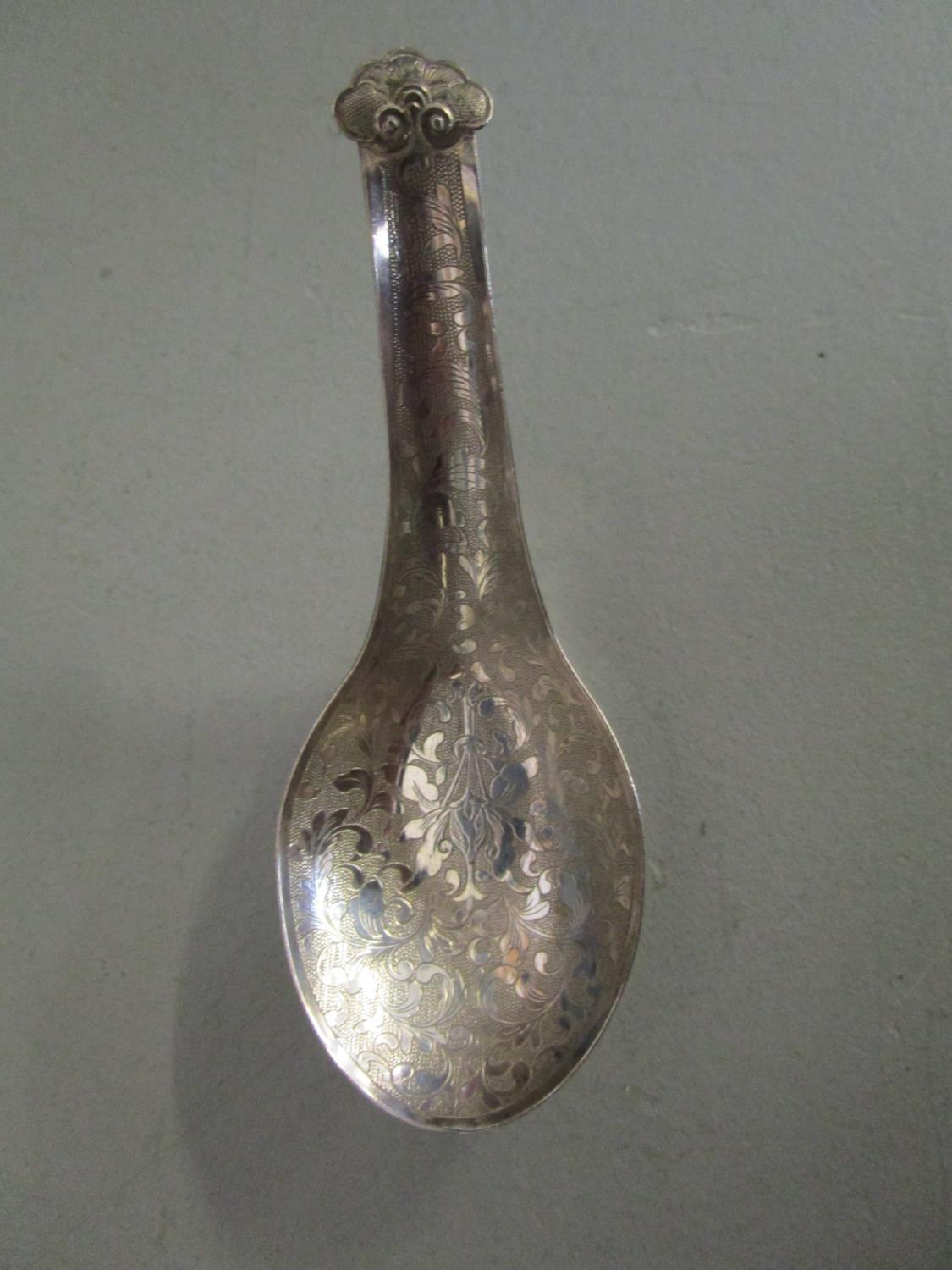 A Chinese silver rice spoon with floral engraved decoration and stylized finial, signed verso,