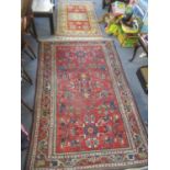 Three rugs to include a Middle Eastern red ground rug having geometric designs 79" x 49", and two