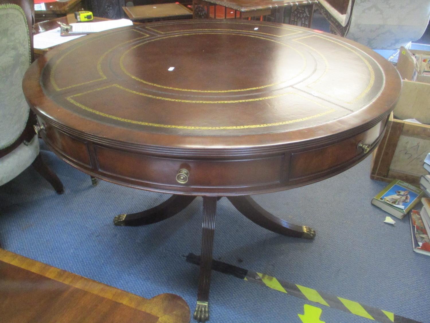A reproduction Regency inspired mahogany drum table having a leather top, fluted column and four