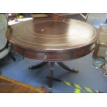 A reproduction Regency inspired mahogany drum table having a leather top, fluted column and four
