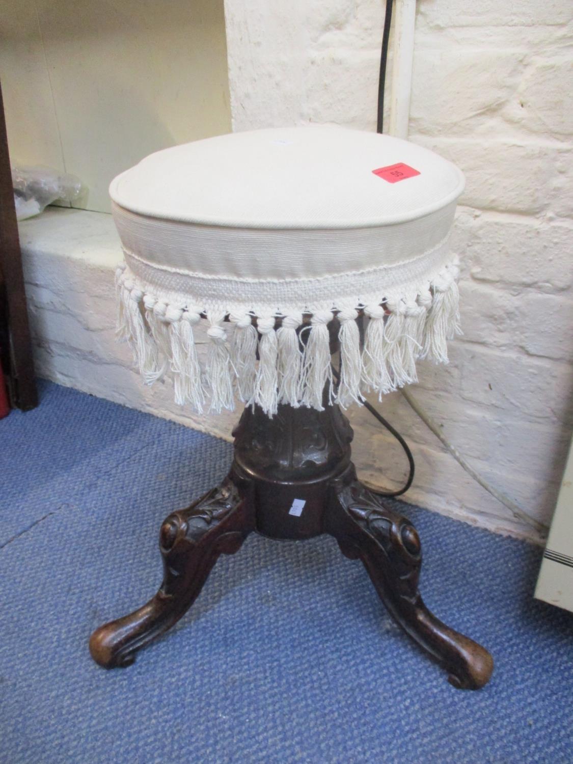 A Victorian carved walnut piano stool with a rotating upholstered seat