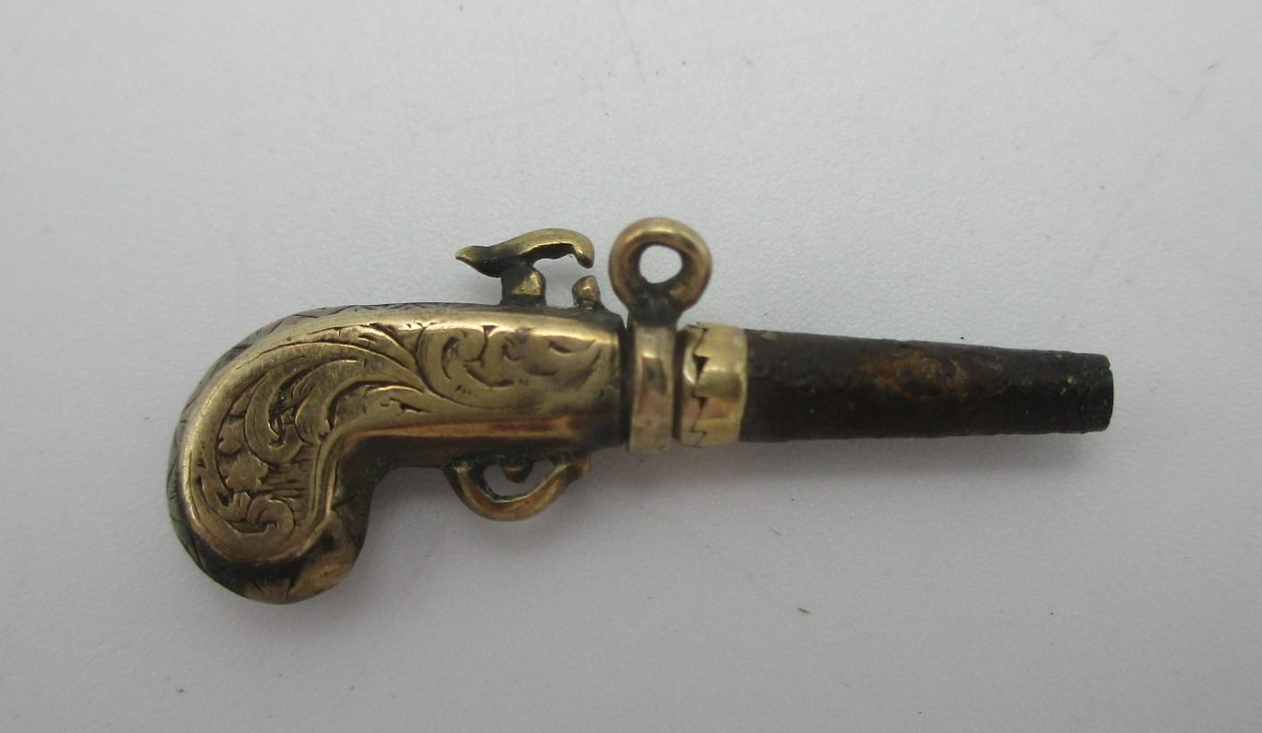 A gold coloured metal and steel watch key fashioned as a pistol with a ratchet mechanism Location: - Image 2 of 3