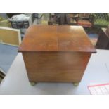 An early 20th century walnut coal box with brass feet