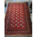 A Pakistan hand woven red ground rug decorated with three rows of nine elephant gulls, multi guard
