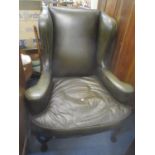 A leather wing backed armchair on cabriole front legs with sabre reverse