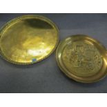 Two large brass trays, one depicting a 19th century pub scene and the other a Middle Eastern example