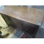 A late 17th/18th century oak coffer having a carved panelled front, a hinged top with inset candle