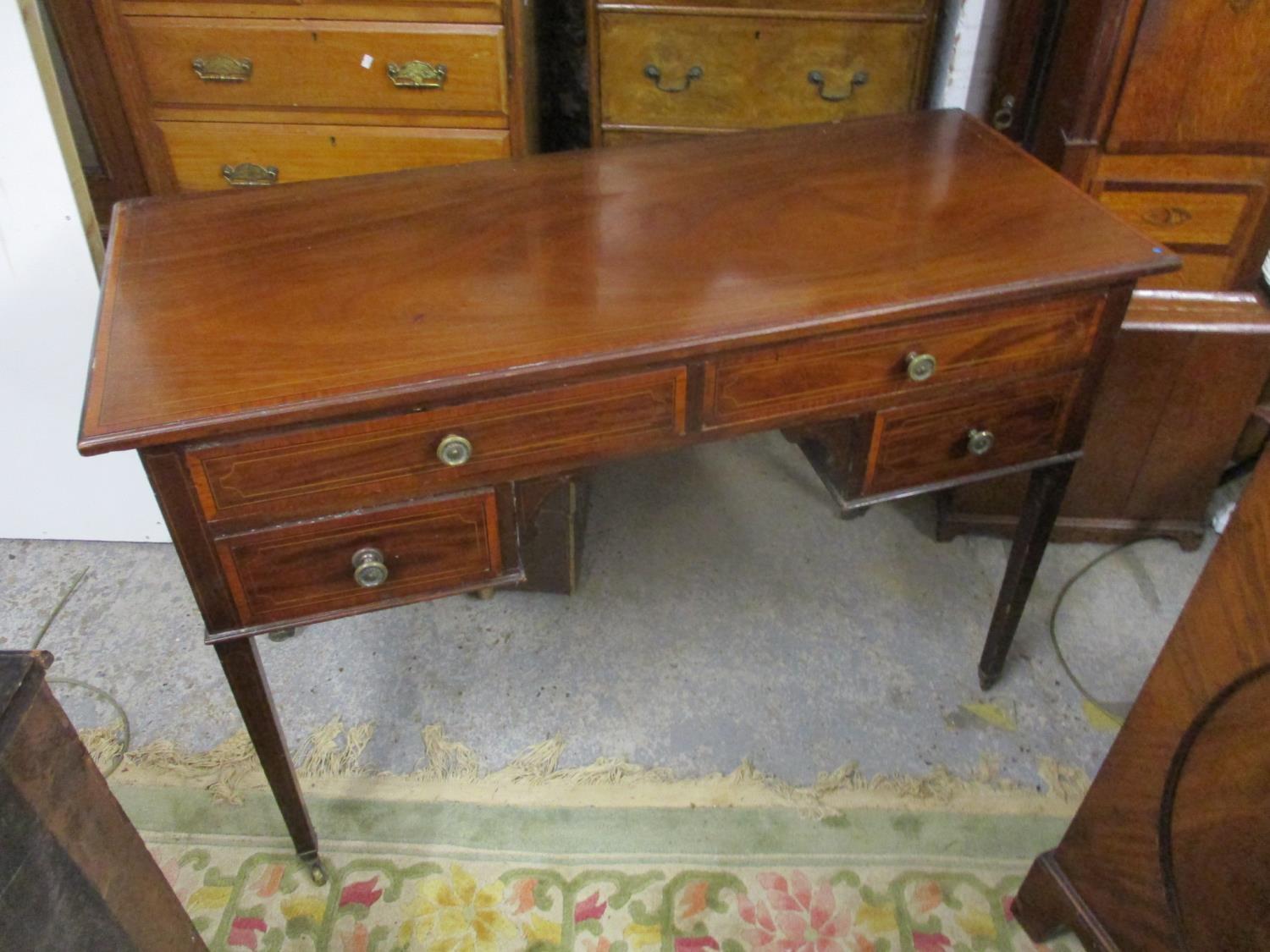 A late Victorian satinwood inlaid mahogany writing desk with four drawers on square tapered legs and