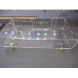 A retro Perspex open coffee table on castors