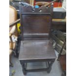 An early 18th century oak chair with a fretworked panelled back and solid seat, on turned block legs