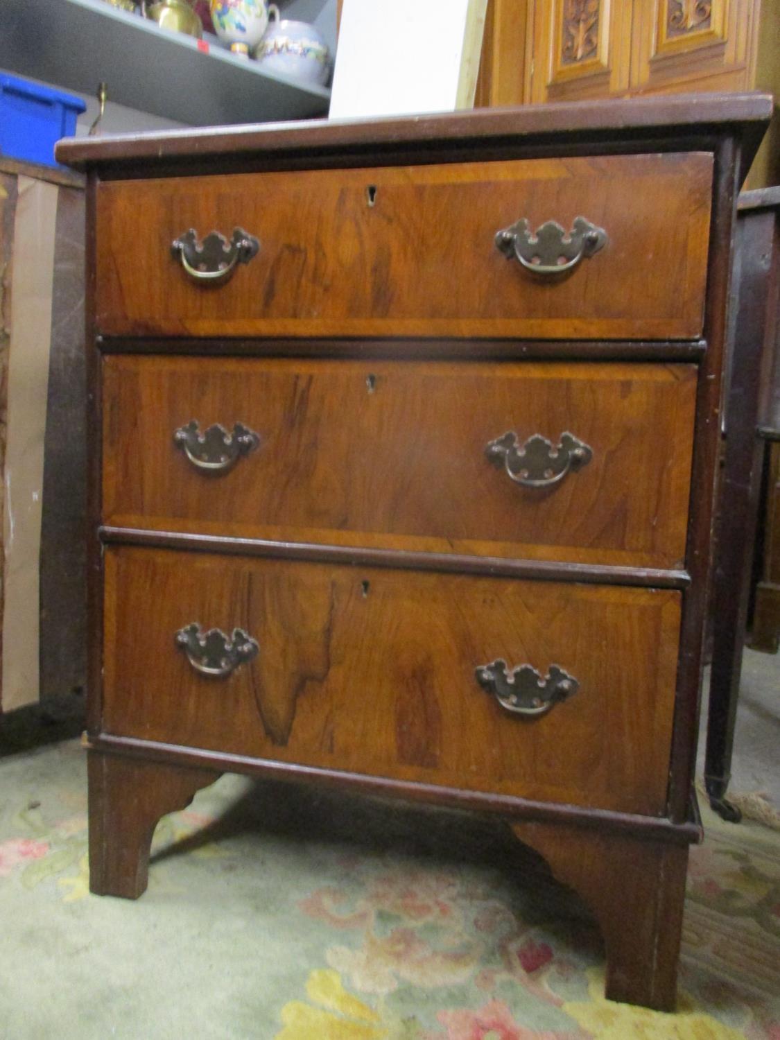 An early 20th century walnut three drawer chest on bracket feet