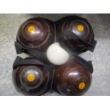 Four lignum vitae bowling balls with a porcelain jack