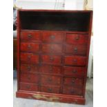 A Chinese lacquered and painted chest with a shelf over eighteen drawers on a plinth