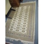 A cream Bokhara rug with tasselled ends