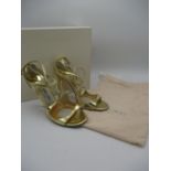 A pair of boxed Jimmy Choo ladies gold coloured high heeled shoes, size 37.5, A/F. Dust cover