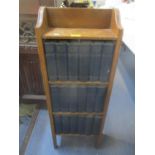 An early 20th century oak three tier open bookcase containing a set of eighteen volumes of Charles