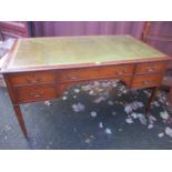 An early 20th century mahogany desk having a green leather topped scriber, five inset drawers and