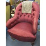 A Victorian button back armchair with mahogany turned front legs, having a burgundy fabric