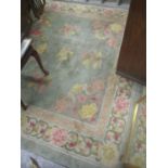 A Chinese green ground rug having a central motif and a floral design, 303cm x 220cm