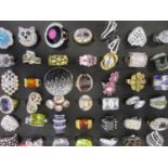 A display of forty four modern dress rings having gold or silver toned bands and paste stones, all