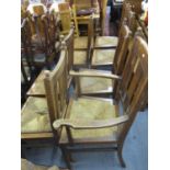 Circa 1900, six standard chairs, one carver and one stool, all in oak with rush seats, the carver