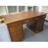 An early 20th century walnut twin pedestal nine drawer desk on plinths