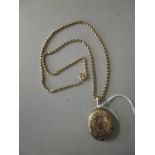 A Victorian/Edwardian gold coloured pendant locket with floral engraved decoration, on a yellow