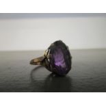 A rose gold coloured amethyst ring with remains of a gold over wash, claw set oval amethyst coloured