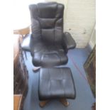 A modern black leather swivel armchair and a matching foot stool. Location:RAF