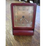 A mid 20th century Jaegar travel clock in a brass and burgundy coloured frame