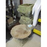 A stone birdbath in the form of a clam shell together with two pedestal stone platers of square form