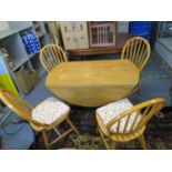 An Ercol style drop flap kitchen table, along with four kitchen chairs having loose attached