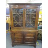 A George III and later oak bookcase having astrigal glazed doors above two panelled cupboard doors