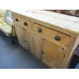 A Victorian pitch pine dresser base/sideboard having two drawers with bun handles above two cupboard