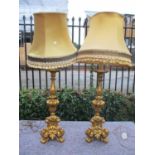 A pair of heavy gilt plaster floor/table lamps with fabric shades
