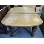 An oak extending dining table with cup and cover turned legs and cross stretchers, two extra leaves,