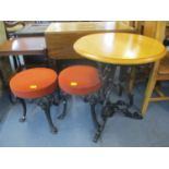 A pub style circular table above ornate wrought iron stand and two similar style stools