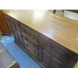 An Ercol dresser base with four central short drawers flaked by fielded cupboards
