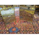 Two Arts and Crafts brass fire screens with inset bevelled mirrors both standing on splayed legs