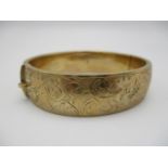 A 9ct gold engraved bangle, designed with etched scrolls of foliage throughout the exterior, 5.8