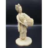 A Japanese Meiji period ivory okimono, modelled as a woman in traditional clothing carrying a basket