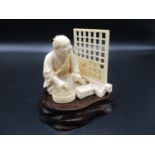 A Japanese Meiji period ivory okimono, modelled as a man possibly repairing a screen, holding a
