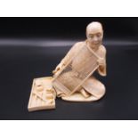 A Japanese Meiji period ivory okimono, modelled as an artisan screen maker at work, his tools by his